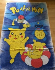A towel that looks like it has pokemon cartoons on it however it is off brand and says Pocheman instead.